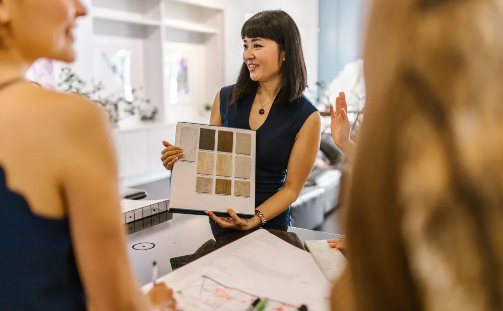 Diseñadora presenta muestras de materiales y acabados a sus clientes en una reunión de estudio.